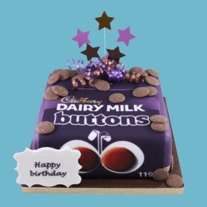 A square Cadbury Dairy Milk Buttons Cake designed to resemble a classic Dairy Milk Buttons packet, featuring the signature purple colour and branded edible image on top. Chocolate button decorations are placed neatly on the cake’s smooth icing surface, adding texture and charm. A custom message plaque sits on the front, with star-shaped toppers completing the festive look. The cake is playful and nostalgic, ideal for birthdays, thank-yous, or chocolate-themed celebrations.
