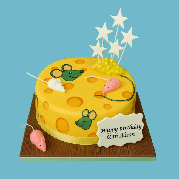 A round novelty cake designed to look like a wedge of cheese, covered in bright yellow icing with hand-crafted holes to mimic real cheese texture. Tiny edible grey mice with pink noses, ears, and tails peek out from around the cake, adding a playful and detailed touch. A personalised message plaque sits on top, surrounded by colourful star-shaped toppers. This fun and whimsical cake is ideal for birthdays, themed parties, or cheese lovers, offering a creative and joyful centrepiece.