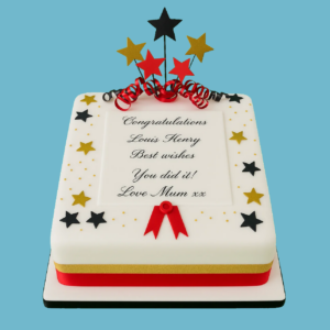 White fondant cake decorated with gold and black star accents, red and gold ribbon trim, and a central plaque for a personalised “Congratulations” message. Designed to celebrate achievements, with optional flavours and sizes available.