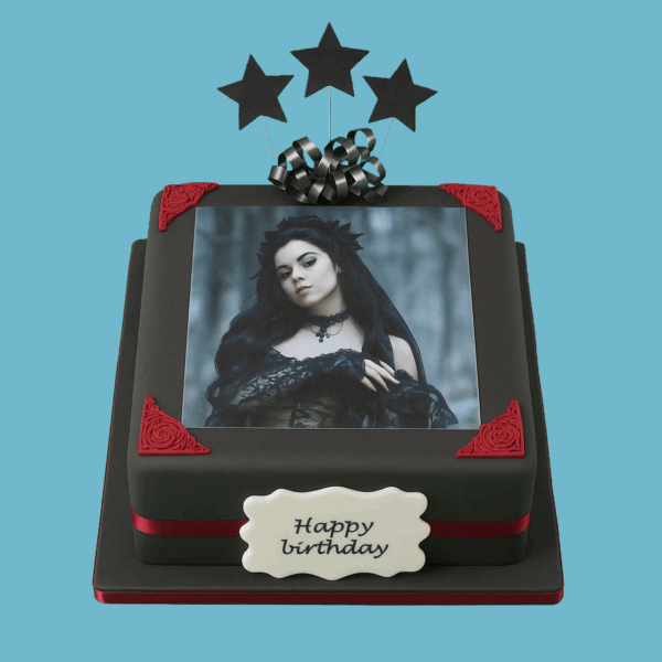A two-tiered square Gothic-style cake covered in dark grey fondant with rich red decorative corners and red ribbons around each tier. The center of the top tier features a framed photo space for personalization. Black star-shaped toppers adorn the top, and a personalized message plaque is displayed on the front. The cake combines bold, dramatic colors and elegant gothic elements, making it a striking centerpiece for special occasions.