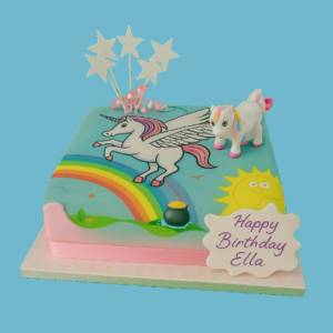 A square celebration cake featuring a colourful unicorn design with a flowing mane, set against a vibrant rainbow background. The cake is decorated with star toppers and a personalised message plaque, creating a festive and magical appearance. Bright colours and whimsical artwork make it a perfect centrepiece for birthdays and fantasy-themed parties.
