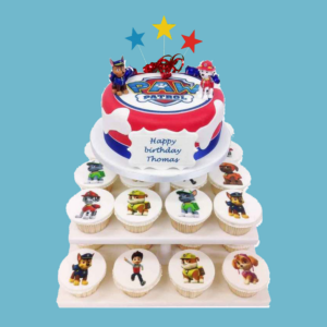 A colourful multi-tiered PAW Patrol cupcake tower with a round cake at the top, decorated with the PAW Patrol logo and characters like Chase, Marshall, Skye, and Ryder. The cake is surrounded by neatly arranged cupcakes featuring edible images of the pups. Bright red, blue, and yellow colours create a lively look. A personalised message plaque sits at the base, with star toppers adding sparkle. The display is festive, sturdy, and perfect for a child’s birthday party or PAW Patrol-themed celebration.