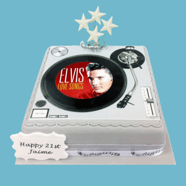 Square cake designed as a record turntable, covered in grey fondant with scalloped edges, a custom photo in the centre, silver and white star toppers, a music note ribbon around the base, and a personalised message plaque on top.