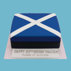A rectangular cake decorated with Scotland’s Saltire flag, featuring a crisp white diagonal cross on a vibrant blue background. Along one side, a detailed strip of traditional red, green, and yellow tartan adds an authentic Scottish touch. The cake’s clean lines and bold colors celebrate Scottish heritage and make a striking centerpiece for cultural or national celebrations.