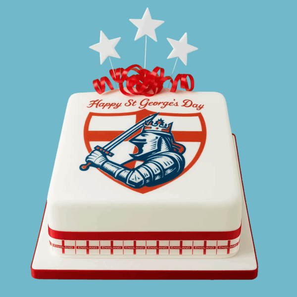 A St. George’s Day Cake decorated with a white fondant base and vivid red ribbons wrapped around its base. The cake features a bold shield design with St. George imagery at the center and the word “England” clearly displayed around it. Red star-shaped toppers sit delicately on top, enhancing the festive and patriotic theme. The cake’s elegant and striking decorations celebrate England’s patron saint, making it perfect for family gatherings or community events.
