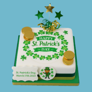 A festive St. Patrick’s Day cake decorated with a vibrant green shamrock wreath encircling its smooth white fondant surface. Gold coin accents and a cheerful leprechaun figure sit atop the cake, symbolizing luck and Irish tradition. Green and gold ribbons wrap around the base, complemented by star toppers and additional ribbon decorations, creating an elegant and celebratory look. The cake can be customized in various flavors and sizes, with options for personalized messages, making it a joyful centerpiece for St. Patrick’s Day gatherings.