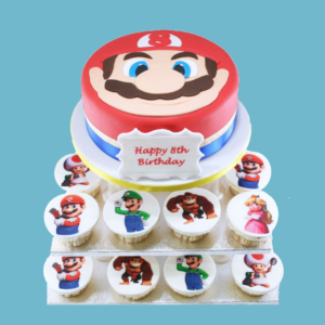 Super Mario-themed cake and cupcake tower featuring a round cake designed as Mario’s face with his red hat and moustache, surrounded by cupcakes decorated with characters like Luigi, Princess Peach, Yoshi, and Toad. Includes a customisable message plaque.