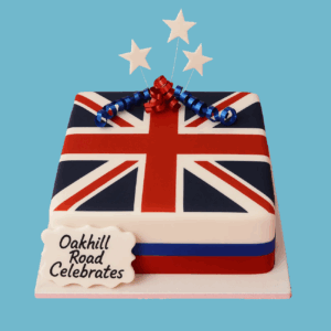 A square cake iced smoothly with a detailed Union Jack flag design in bright red, white, and blue. On top, a personalised message plaque and small decorative star toppers add festive touches. The cake has clean, sharp lines and vibrant colors, making it a striking centerpiece for celebrations of British pride, national holidays, or royal events.
